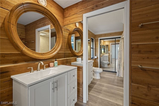 bathroom featuring hardwood / wood-style floors, wood walls, vanity, ornamental molding, and toilet