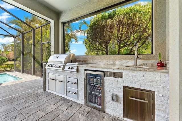 view of patio with an outdoor kitchen, sink, area for grilling, and glass enclosure