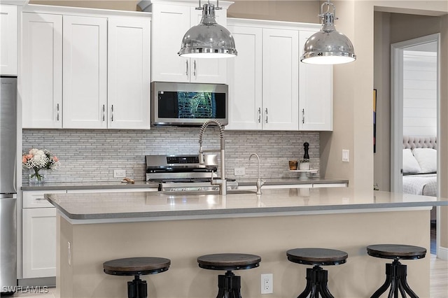 kitchen with stainless steel appliances, a breakfast bar, and white cabinets