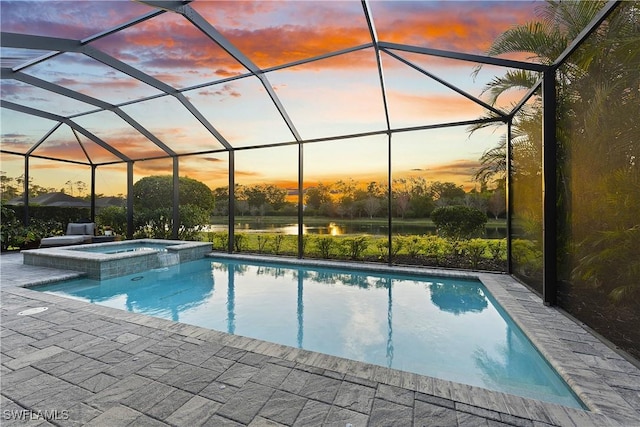 pool at dusk featuring an in ground hot tub, a patio area, and glass enclosure