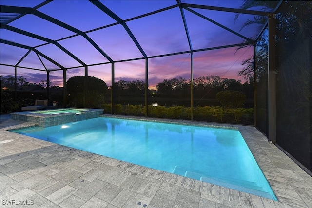 pool at dusk featuring an in ground hot tub, a lanai, and a patio