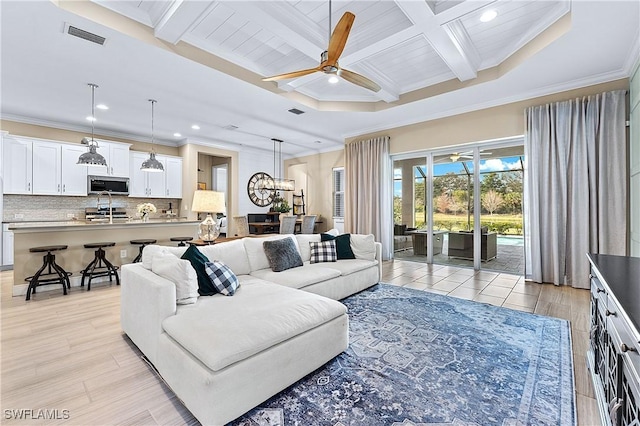 living room with beam ceiling, ornamental molding, coffered ceiling, and ceiling fan