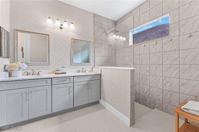 bathroom with vanity, tile patterned flooring, tile walls, and a tile shower