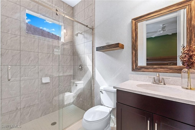 bathroom with a shower with door, vanity, ceiling fan, and toilet