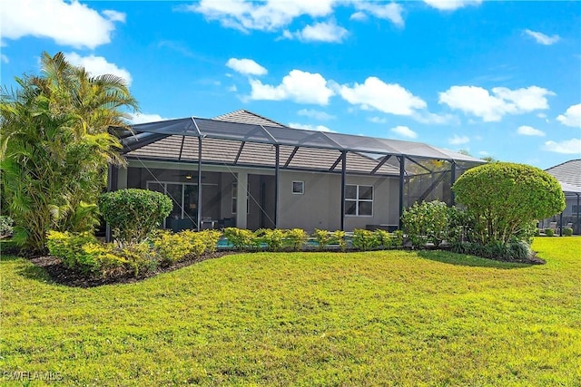 rear view of property featuring a lawn and glass enclosure