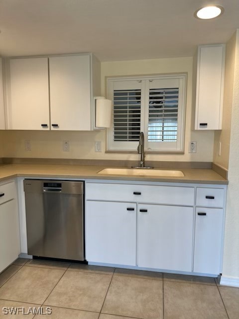 kitchen featuring stainless steel dishwasher, light tile patterned floors, sink, and white cabinets