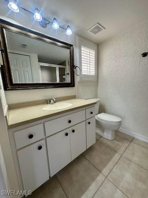 bathroom featuring vanity, tile patterned flooring, a shower with shower door, and toilet