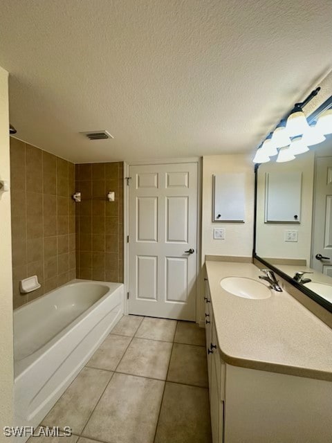 bathroom with tiled shower / bath, vanity, tile patterned flooring, and a textured ceiling