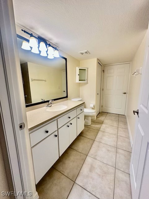 bathroom featuring vanity, tile patterned floors, toilet, and a textured ceiling