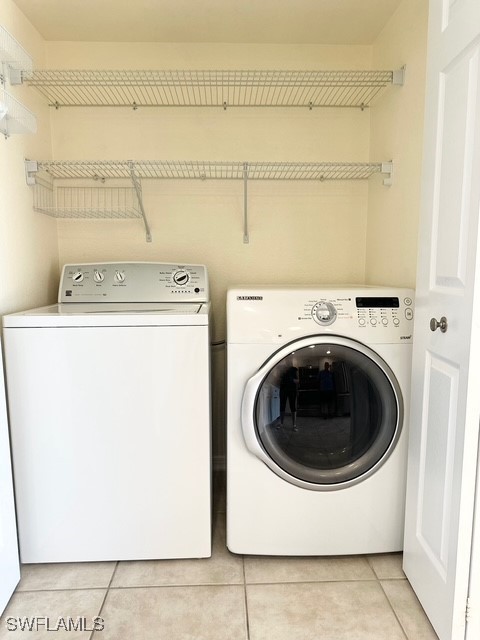 washroom with washing machine and dryer and light tile patterned floors