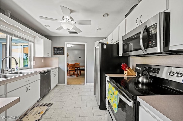 kitchen featuring white cabinetry, sink, light tile patterned floors, ceiling fan, and stainless steel appliances