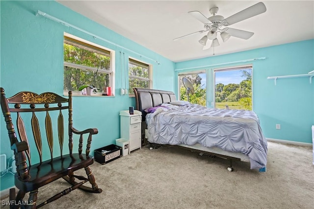 carpeted bedroom with multiple windows and ceiling fan