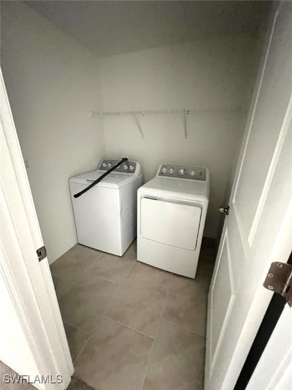 laundry area with separate washer and dryer and light tile patterned floors