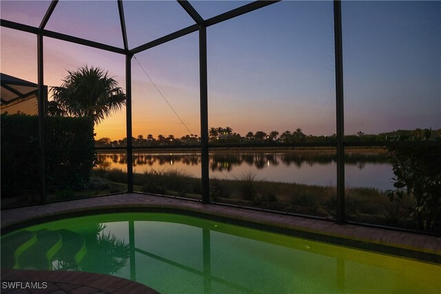 pool at dusk with glass enclosure and a water view