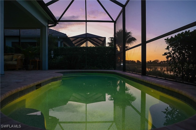 pool at dusk featuring a lanai and a patio