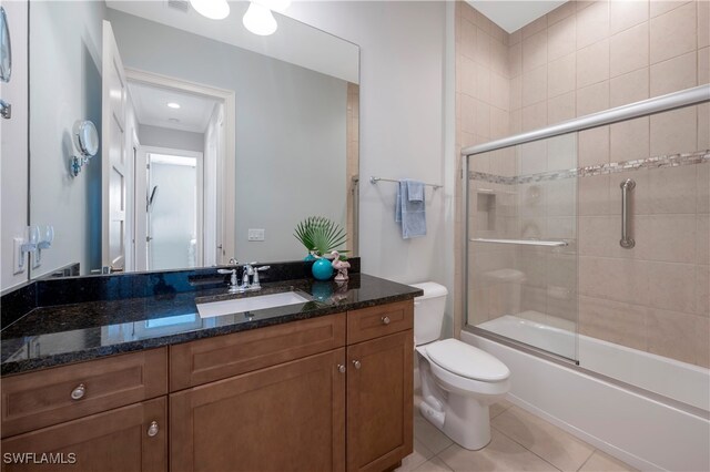 full bathroom with tile patterned flooring, vanity, enclosed tub / shower combo, and toilet