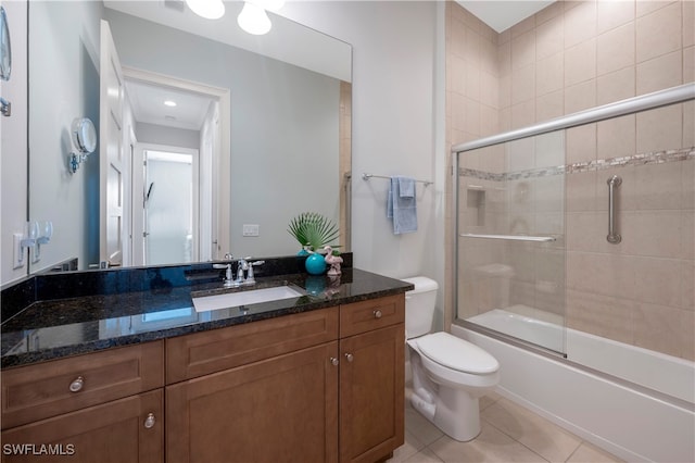 bathroom with toilet, tile patterned flooring, combined bath / shower with glass door, and vanity