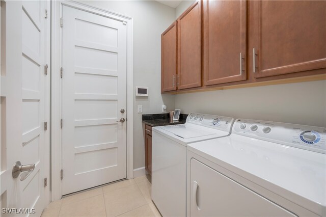 clothes washing area with cabinets, washing machine and dryer, and light tile patterned flooring