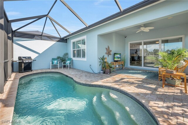 view of pool featuring ceiling fan, grilling area, a patio, and glass enclosure