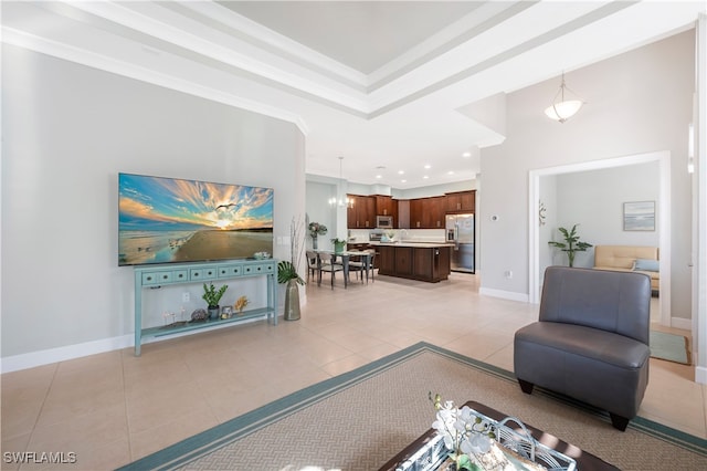 tiled living room with a towering ceiling, ornamental molding, and a tray ceiling