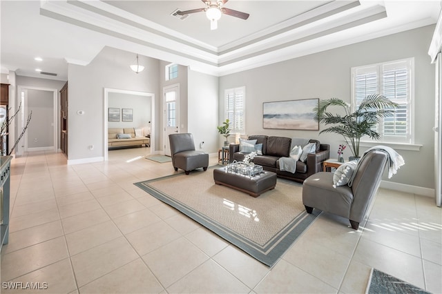 tiled living room featuring a tray ceiling, plenty of natural light, and ornamental molding