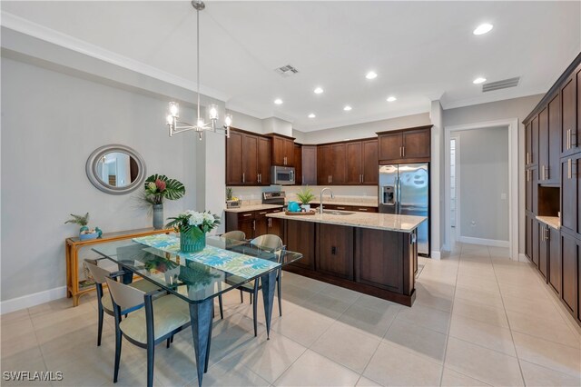 kitchen featuring sink, hanging light fixtures, dark brown cabinetry, stainless steel appliances, and light stone countertops