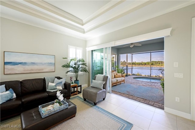 living room featuring light tile patterned floors, ceiling fan, a water view, a tray ceiling, and ornamental molding