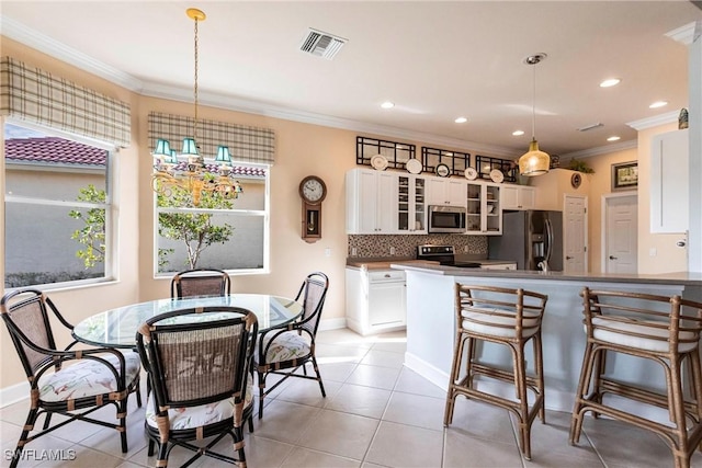 kitchen featuring white cabinetry, decorative light fixtures, ornamental molding, appliances with stainless steel finishes, and backsplash