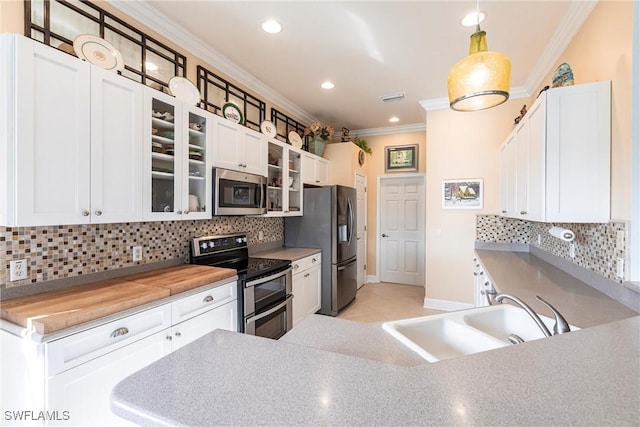 kitchen featuring pendant lighting, sink, white cabinetry, stainless steel appliances, and wood counters