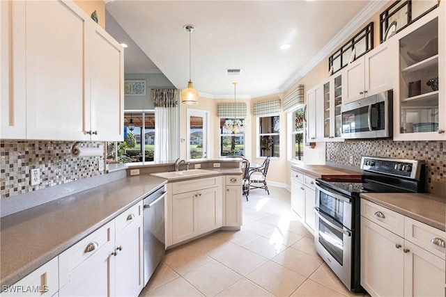 kitchen with pendant lighting, sink, white cabinets, ornamental molding, and stainless steel appliances