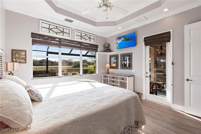 bedroom featuring crown molding, a tray ceiling, wood-type flooring, and ceiling fan