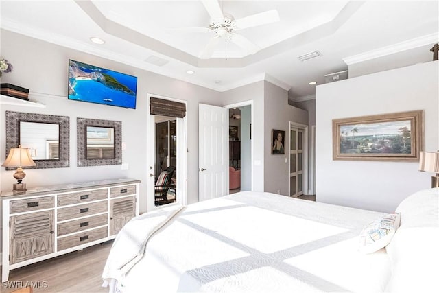 bedroom featuring crown molding, ceiling fan, access to exterior, a tray ceiling, and wood-type flooring