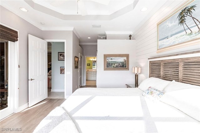 bedroom with connected bathroom, ornamental molding, ceiling fan, light hardwood / wood-style floors, and a raised ceiling