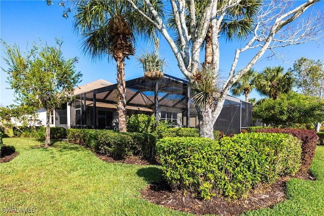 rear view of property featuring a lanai and a lawn