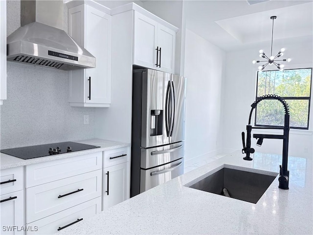 kitchen with wall chimney range hood, sink, white cabinetry, light stone countertops, and stainless steel fridge with ice dispenser