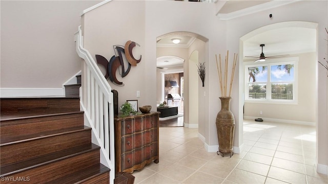 interior space with arched walkways, stairs, a ceiling fan, and light tile patterned floors