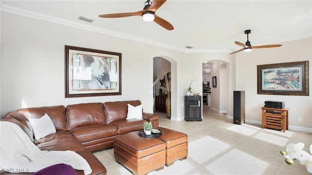 living area featuring ornamental molding, light tile patterned flooring, arched walkways, visible vents, and a ceiling fan