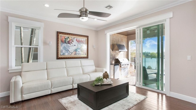 living room with wood finished floors, ornamental molding, baseboards, and visible vents