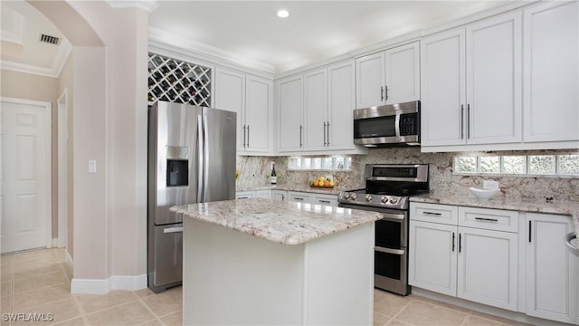 kitchen featuring light tile patterned flooring, a kitchen island, tasteful backsplash, stainless steel appliances, and visible vents