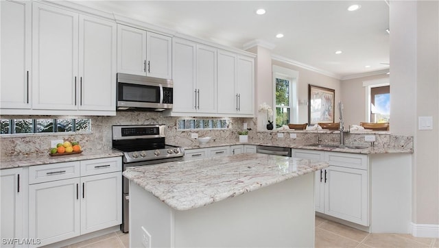 kitchen featuring light tile patterned flooring, a center island, appliances with stainless steel finishes, a sink, and backsplash