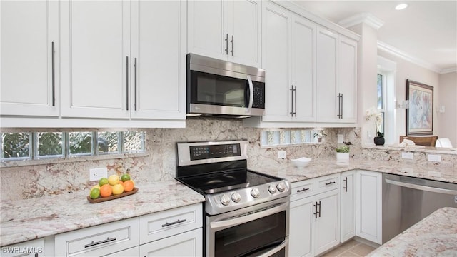 kitchen featuring stainless steel appliances, ornamental molding, decorative backsplash, and white cabinetry