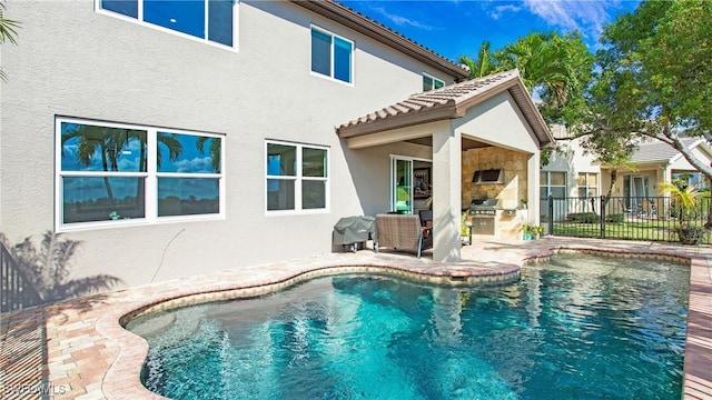 view of pool featuring a patio, fence, grilling area, exterior kitchen, and a fenced in pool