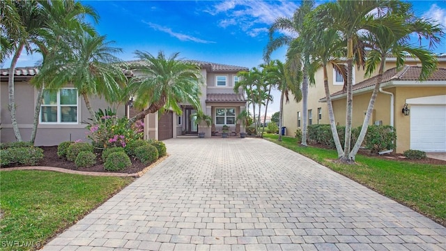 view of front of home with a front lawn, a tiled roof, decorative driveway, and stucco siding