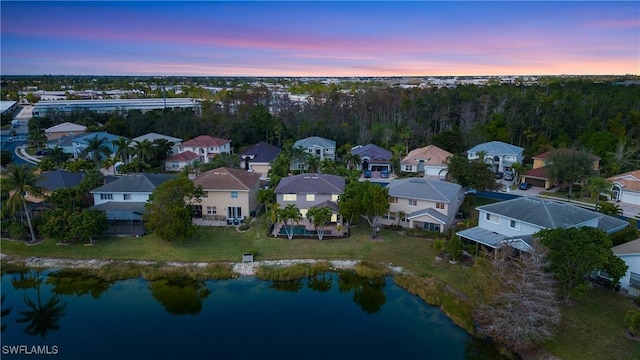 aerial view at dusk with a residential view and a water view