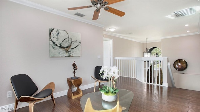 living area featuring visible vents, baseboards, ornamental molding, wood finished floors, and a ceiling fan