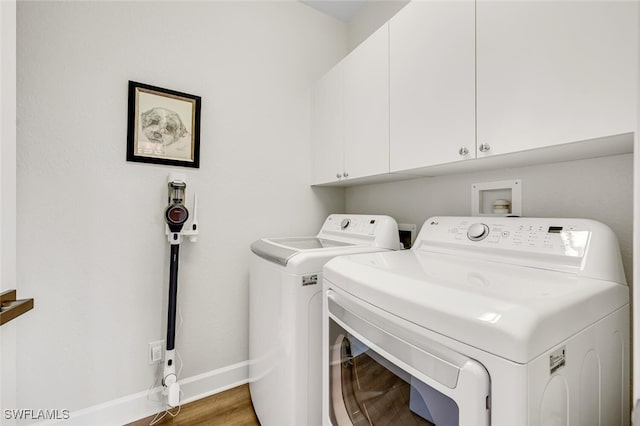 clothes washing area with hardwood / wood-style flooring, washer and clothes dryer, and cabinets