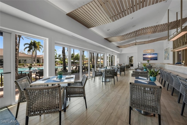 dining space with high vaulted ceiling and light wood-type flooring