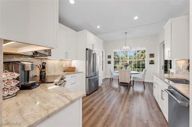 kitchen with light stone countertops, appliances with stainless steel finishes, white cabinets, and decorative light fixtures