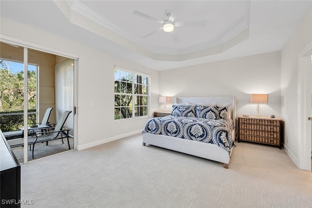 carpeted bedroom featuring multiple windows, a tray ceiling, and access to outside