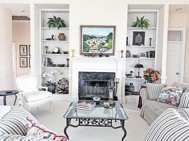 living room with built in shelves, a high end fireplace, decorative columns, and carpet floors